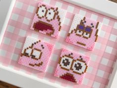 four cross stitch coasters are displayed in a white frame on a pink and white checkered tablecloth