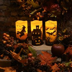 three halloween lanterns sitting on top of a table next to pumpkins and other decorations