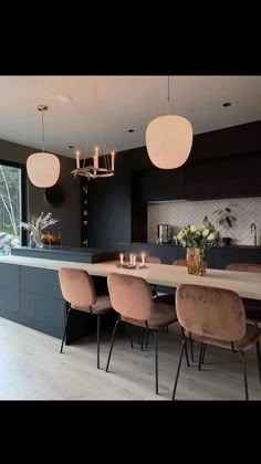 a dining room table surrounded by chairs with candles on it and lights hanging from the ceiling