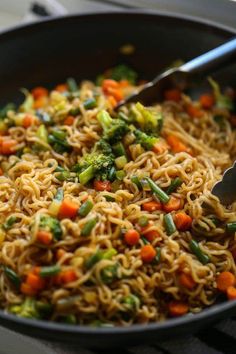 a pan filled with noodles and vegetables on top of a table