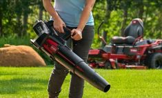 a woman is using a lawn mower to cut grass