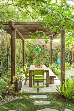 an outdoor dining area with green chairs and a wooden table surrounded by greenery in the background