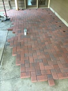 a red brick walkway with a can of soda on it and a door in the background