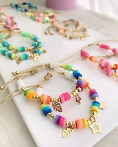 several colorful bracelets with charms on a white tray next to a pink cup and coffee mug