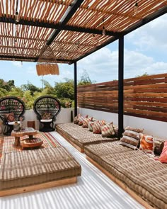 an outdoor living area with couches, tables and wicker screens on the wall