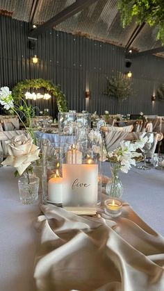 the table is set with candles, flowers and glass vases for an elegant wedding reception