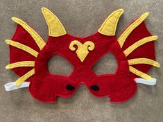 a red mask with yellow and white designs on it's face is laying on the floor