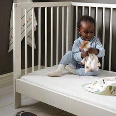 a small child playing with stuffed animals in a crib