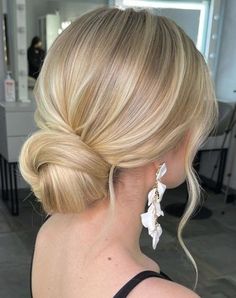 a woman with blonde hair in a low bun and white flowers on it's side