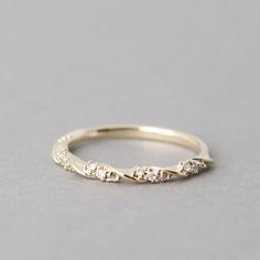 a yellow gold ring with five diamonds on it, sitting on a gray surface in front of the camera