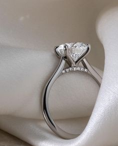 a close up view of a diamond ring on a white cloth with the fabric draped around it