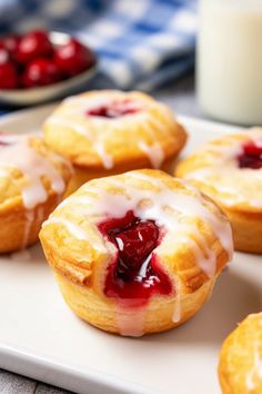 several small pastries on a white plate next to a glass of milk and strawberries