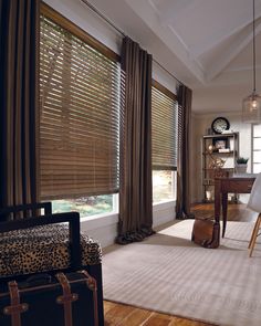 a living room filled with furniture and windows covered in blindes next to a desk