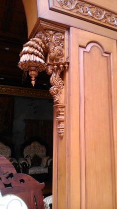 an ornate light fixture is hanging from the side of a wooden door with carvings on it