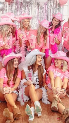 a group of women in pink shirts and hats posing for a photo with balloons behind them