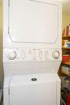 a white washer and dryer sitting in a room next to shelves with other items