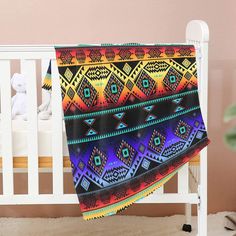 a baby crib with a colorful blanket hanging from it's side