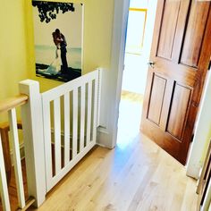 an open door leading to a hallway with a painting on the wall and wooden stairs