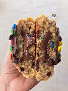 two cookies with chocolate frosting and m & m's on top are being held up