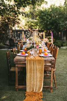 an outdoor dinner table set with oranges and candles