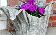 some purple flowers are in a cement vase