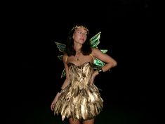 a woman in a gold and green fairy costume standing with her hands on her hips