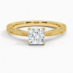 a yellow gold engagement ring with a princess cut diamond in the center and filigree band