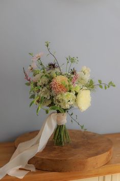 a bouquet of flowers sitting on top of a wooden table next to a white ribbon