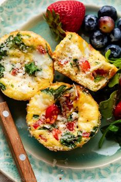 an egg muffin with spinach, cheese and berries on a blue and white plate