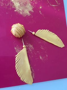 two pieces of carved wood are on a pink surface and one piece is shaped like a shell