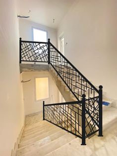 an empty room with white walls and black railings on the second floor, next to a set of stairs