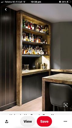 a bar with stools and bottles on the shelves in front of it, next to a counter