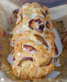 a close up of a pastry with icing and fruit on it in a wrapper