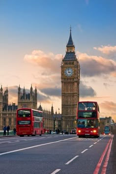 two red double decker buses driving past big ben