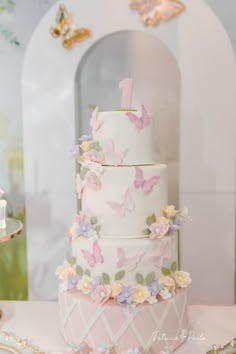 a three tiered cake with butterflies on it