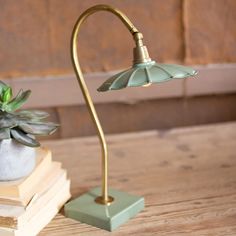 a green lamp sitting on top of a wooden table next to a potted plant