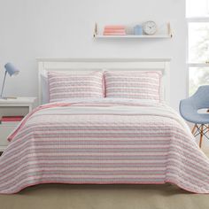 a bed with pink and white bedspread in a room