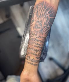 a person with a tattoo on their arm holding up a hand and praying to god