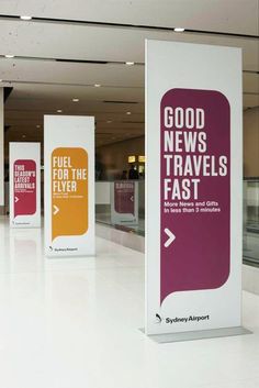 an airport lobby with several signs on the floor and in front of them that say good news travels fast