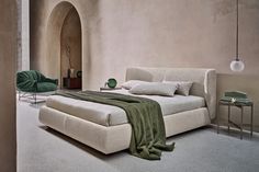 a large bed sitting next to a green chair in a room with beige walls and flooring