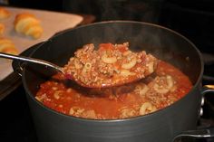 a ladle full of food cooking on the stove