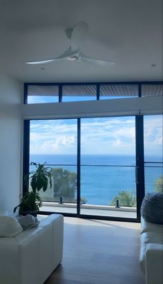 a living room filled with furniture and a large window overlooking the ocean in front of it