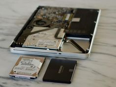 an open laptop computer sitting on top of a white table next to a hard drive