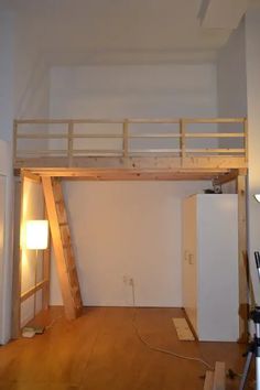 an empty room with a loft bed and ladder on the wall, next to a lamp