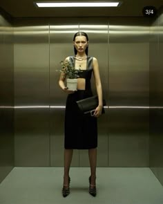 a woman standing in an elevator holding a potted plant