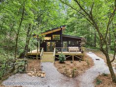 a cabin in the woods with stairs leading up to it's deck and patio