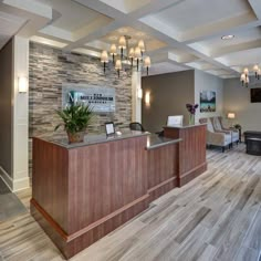 the front desk of a hotel lobby with wood floors and stone accent wall behind it