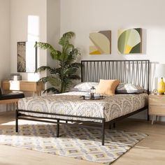 a bed sitting on top of a wooden floor next to a plant in a bedroom