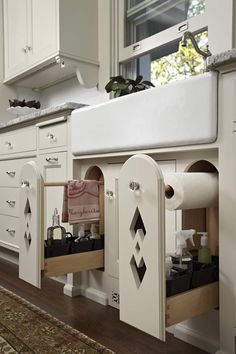 a kitchen with white cabinets and drawers under a window next to a rug on the floor