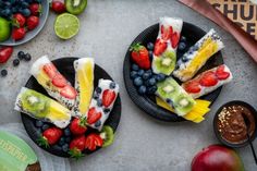 two plates filled with fruit on top of a table next to bowls of fruit and dips